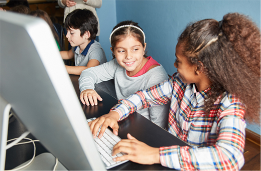 Two young girls working on a computer during school