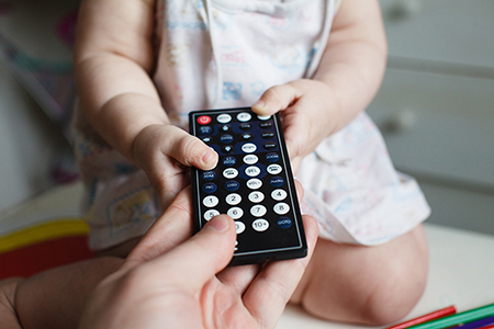 A young child grabbing a remote control